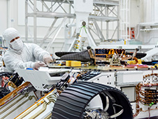 An engineer works on attaching NASA's Mars Helicopter to the belly of the Mars 2020 rover