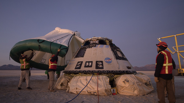 Boeing, NASA, and U.S. Army personnel work around the Boeing Starliner spacecraft shortly after it landed in White Sands, N.M., Sunday.