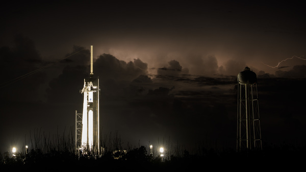 The Dragon crew capsule sits atop a Falcon 9 rocket on Friday as distant storms roll by. NASA and SpaceX cannot launch unless the weather is perfect.