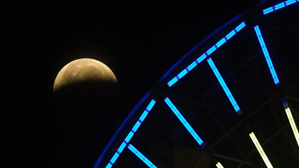 The lunar eclipse progresses behind a ferris wheel over Santa Monica Beach in Santa Monica, Calif., on Wednesday. The first total lunar eclipse in more than two years is coinciding with a supermoon.