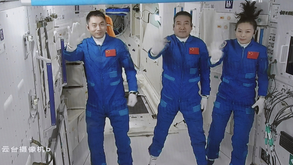 A screen image captured at Beijing Aerospace Control Center in Beijing on Saturday shows Chinese astronauts Ye Guangfu (from left), Zhai Zhigang and Wang Yaping waving after entering the Chinese space station.