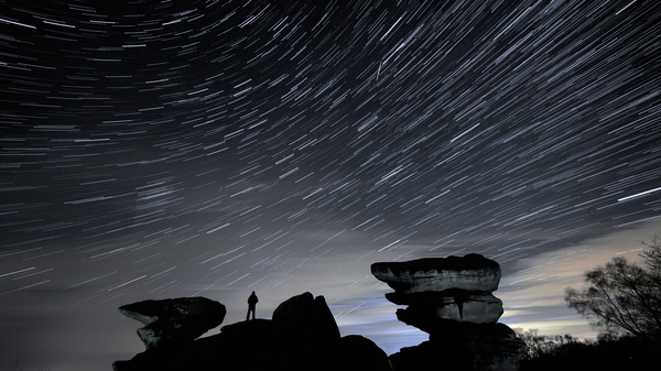 A man watches a meteor during the Geminid meteor shower over Brimham Rocks in North Yorkshire.