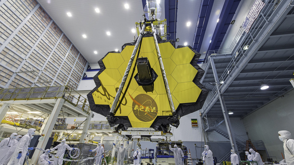 In this April 13, 2017 photo provided by NASA, technicians lift the mirror of the James Webb Space Telescope using a crane at the Goddard Space Flight Center in Greenbelt, Md. The telescope is designed to peer back so far that scientists will get a glimpse of the dawn of the universe about 13.7 billion years ago and zoom in on closer cosmic objects with sharper focus.