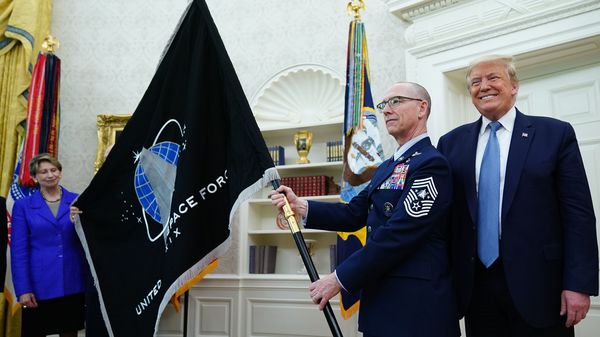 President Trump presedisplays the U.S. Space Force flag in the Oval Office last May. The new command plans to move its headquarters from a temporary location in Colorado to Alabama in 2023.