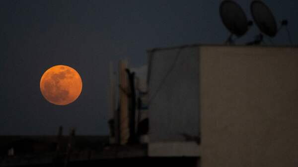 The Super Blood Moon rises over a residential area in New Delhi during a total lunar eclipse on May 26, 2021.