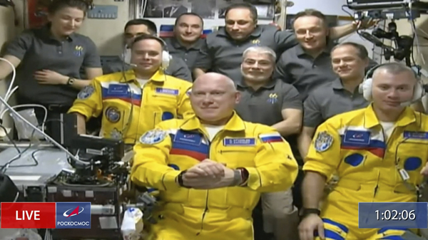 Russian cosmonauts Sergey Korsakov (from left), Oleg Artemyev and Denis Matveyev are seen wearing yellow and blue during a welcome ceremony after arriving at the International Space Station.