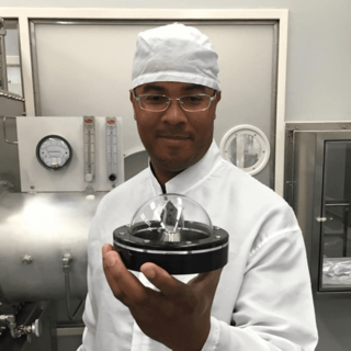 Christopher Snead, OSIRIS-REx deputy sample curator, the curation small particle handling lead and OSIRIS-REx deputy curator, holding a preserved Moon rock in Johnsons curation laboratory.