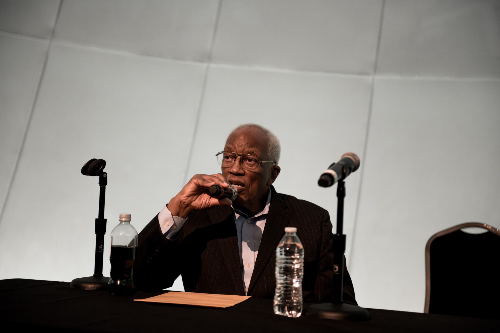 Guy Bluford sits in front of a microphone at Great Lakes Science Center in Cleveland. He discusses his historic shuttle flight. A giant domed screen is in the background.