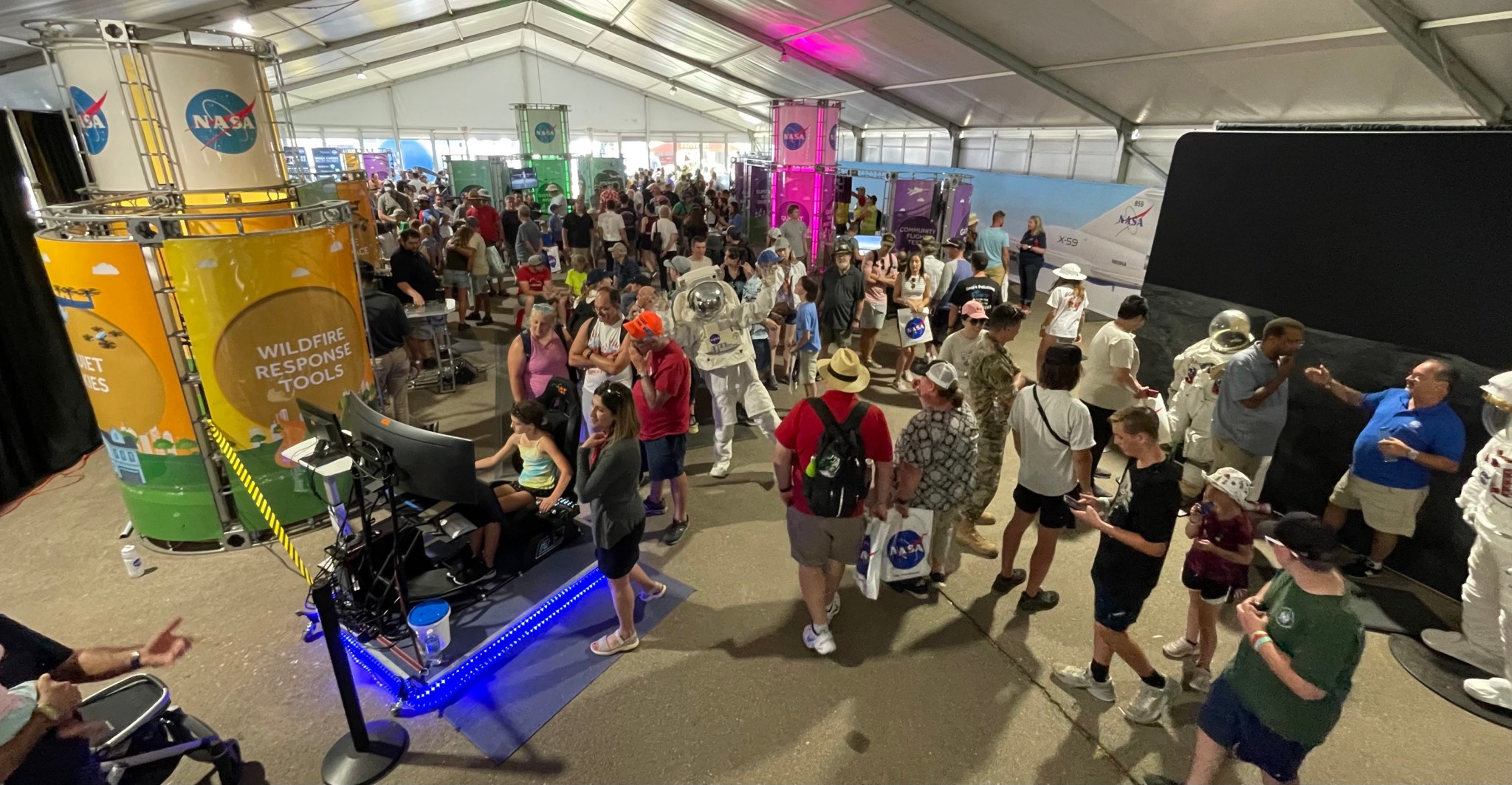 Mark Frances shows a young boy how to use his goggles and controls to experience interactive technology. They are inside a tent.